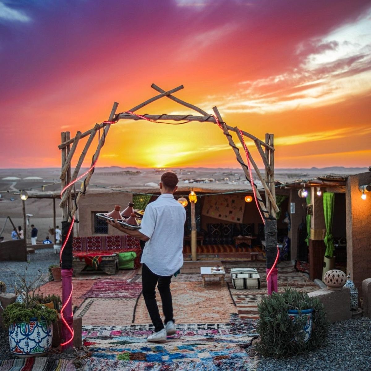 Traveller photographing the sunset through a wooden arch at the camp